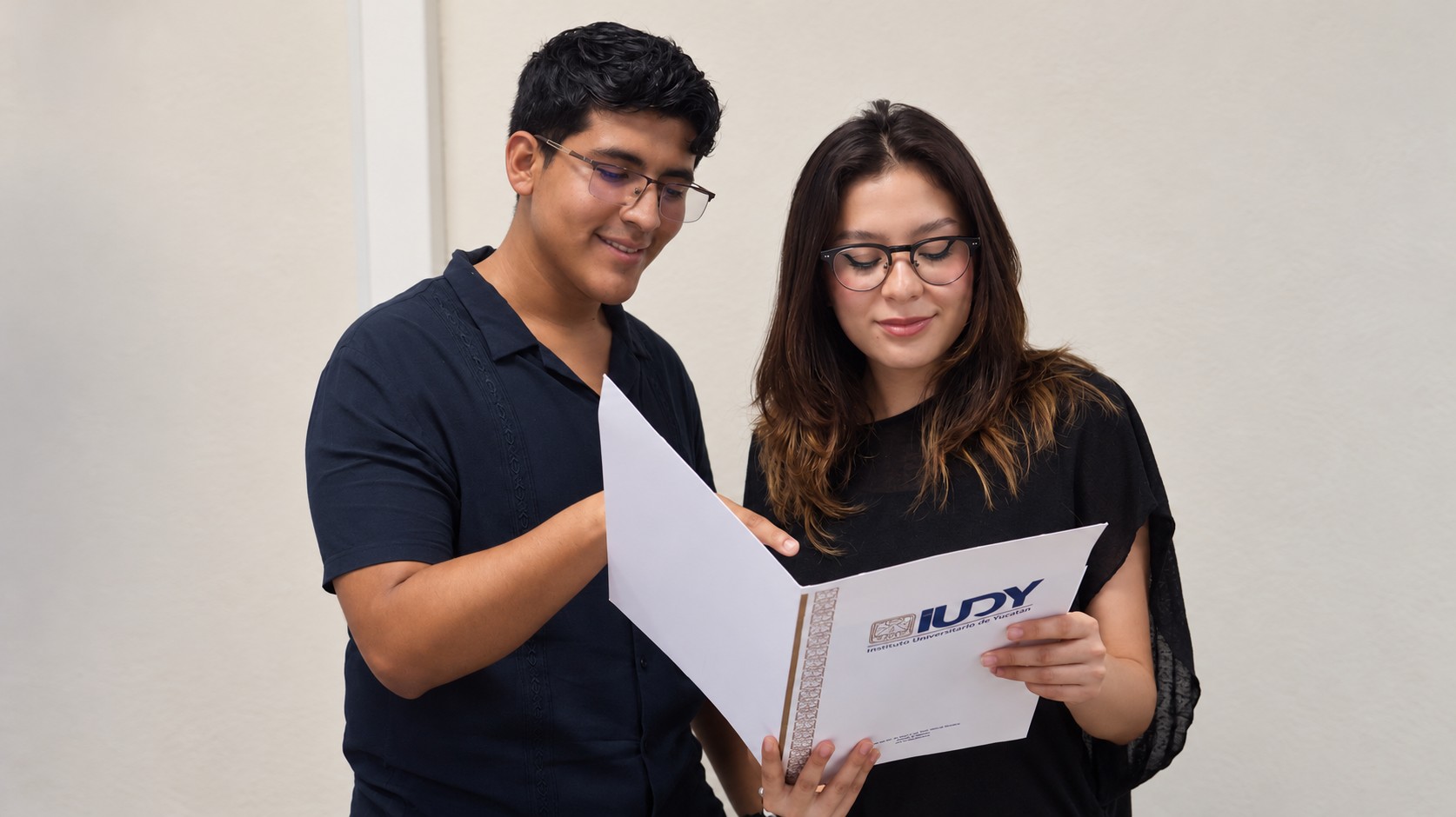Dos estudiantes revisan juntos una carpeta académica de IUDY